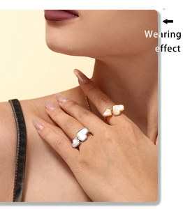 Close-up of gold and silver heart-shaped mother of pearl rings worn on fingers