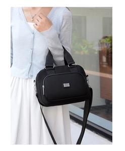 Detail of waterproof black nylon handbag with silver logo and adjustable shoulder strap