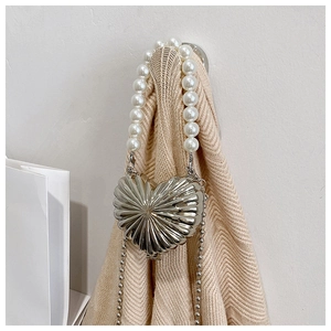 Macro shot of silver heart-shaped metal bag featuring pearl handle and chain strap