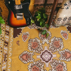 Detail of bohemian woven blanket featuring ginger floral patterns and tassel edges