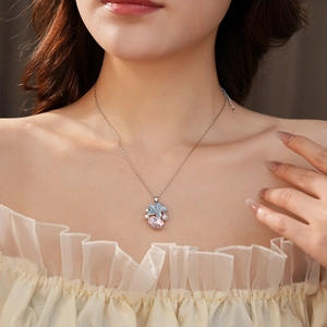 Détail du collier avec fleur bleue, gemme rose et perle blanche porté par le mannequin