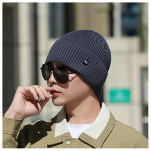 Gros plan du bonnet en maille gris foncé avec une petite étiquette logo 'ny' noire
