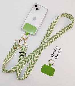 Close-up of printed fabric phone strap with green leaf patterns and gold metal buckles