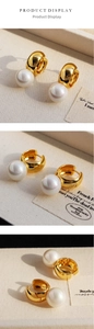 Detail view of gold hoop earrings with large lustrous white pearls on fabric