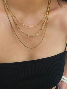Close-up of triple-layered gold snake and twisted chain necklace on a female model