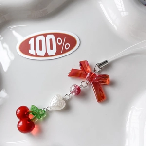 Macro detail of red cherry and strawberry charm with resin heart on a white tray