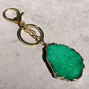 Detail of green natural crystal agate stone keychain with gold-plated edges and metal clasp