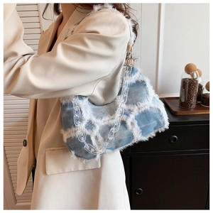 Detail of denim and white faux fur texture with transparent acrylic chain on shoulder bag