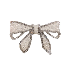 Barrette nœud élégante ornée de perles et strass brillants sur fond blanc épuré
