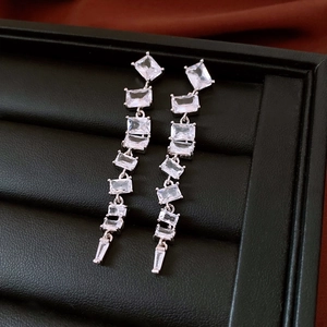 Vue détaillée de boucles d'oreilles argentées avec zircon sur support à bijoux noir