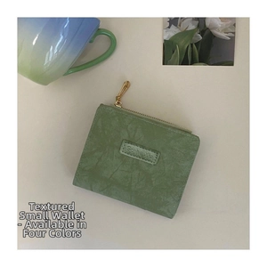 Close-up of light green vintage mini wallet with gold zipper and smooth matte texture