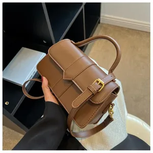 Détail d'un sac bandoulière vintage marron avec coutures verticales et boucle dorée