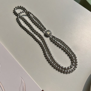 Detail of double-layer grey pearl necklace featuring a square shell pendant with crystals