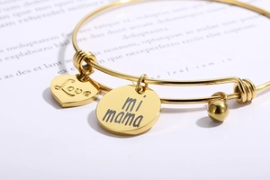 Vue macro des pendentifs cœur et rond en acier doré avec gravure Love mi mama