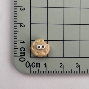 Detailed close-up of a 1cm mini resin cookie charm with eyes on a measuring mat