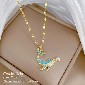 Detail view of gold whale pendant with blue enamel, zircon accents and pearl on box