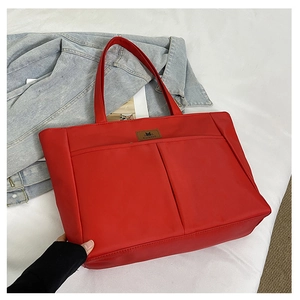 Detail of red large capacity tote bag featuring dual front pockets and shoulder straps