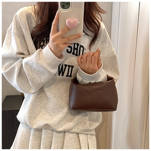 Detail of dark brown embossed mini crossbody bag paired with a grey casual outfit
