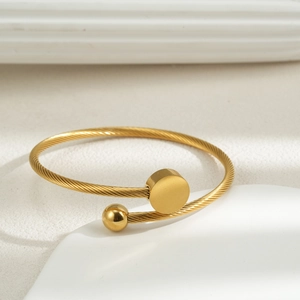Detailed shot of golden braided stainless steel open bangle with bead and disk ends