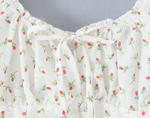 Detail der Blumenprint-Bluse mit Bindebogen-Ausschnitt und Rüschenkanten in Weiß