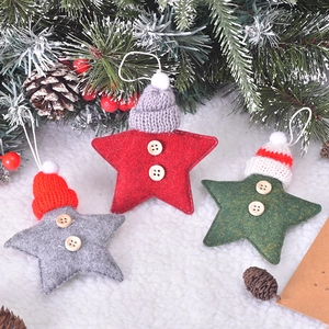 Three felt star Christmas ornaments with knit hats and wooden buttons on pine branches
