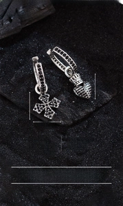 Close-up of asymmetric silver-plated earrings with black zircon cross and crown heart