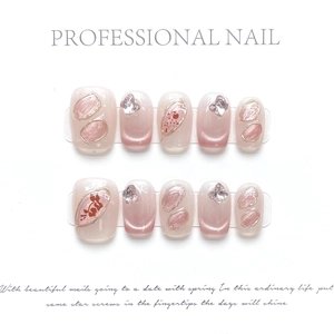 Detail of handmade cat-eye press-on nails with pink gradients and gold leaf accents