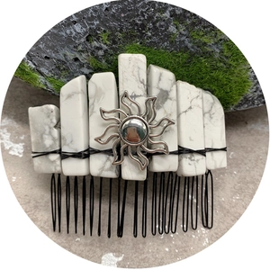 Natural white crystal hair comb with silver sun charm on a mossy stone background
