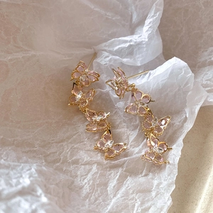 Detailed macro view of pink crystal butterfly tassel earrings with golden metal chains