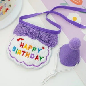 Close-up of purple and white pet birthday bib and plush hat with happy birthday embroidery