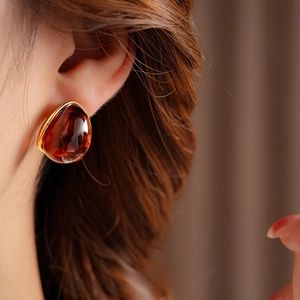 Macro view of vintage round resin earring with golden frame on model ear