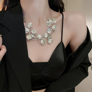 Detail of silver leaf-shaped metal necklace on model with layered design texture
