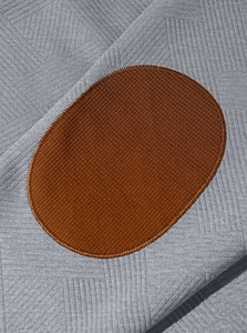 Gros plan sur un tissu en maille jacquard gris avec un empiècement coude ovale marron