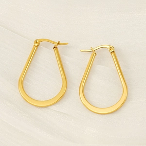 Polished gold U-shaped hoop earrings on silk fabric background, minimalist jewelry for women