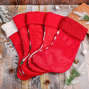 Set of 4 red knitted Christmas stockings with white cuffs on rustic wooden background