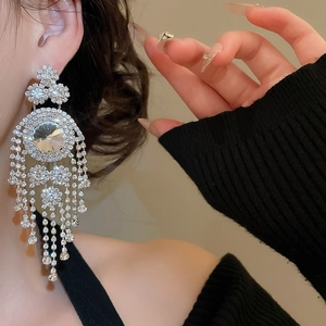 Close-up of geometric tassel earrings with brilliant rhinestones on a model