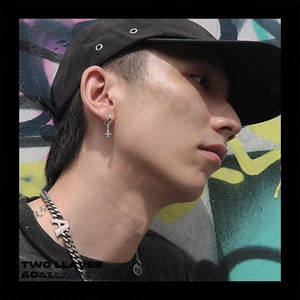 Close-up of a silver cross hoop earring and letter A chain necklace on a male model