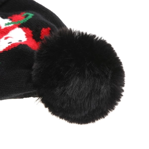 Macro detail of Christmas knit hat showing black pom-pom and festive pattern textures
