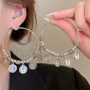 Close-up of vintage hoop earrings with Elizabeth II coin charms in silver finish