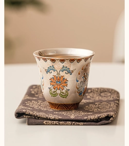 Close-up of fine ceramic tea cup with intricate enamel floral patterns and textures