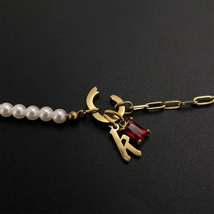 Elegant titanium steel necklace featuring letter K pendant, red gemstone and pearls.