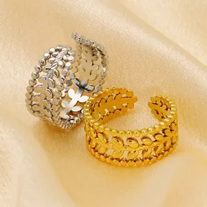 Macro detail of gold and silver olive leaf rings on golden silk background texture