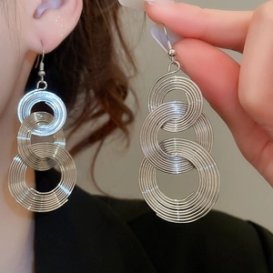 Close-up of silver metal multi-layered circular coil earrings on model