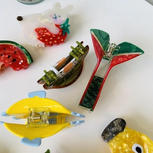 Flat lay of colorful acetate fruit hair claws like strawberry and duck on white surface