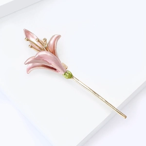 Detailed view of enamel daffodil brooch with pink gradient petals and gold stem accents