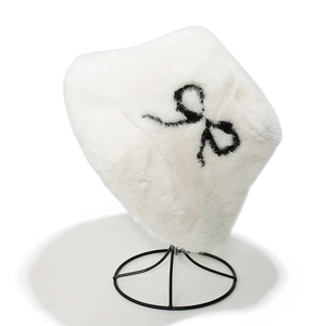 Close-up of a white plush bucket hat with a black embroidered bow on a metal stand