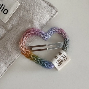 Detail of a rainbow crochet heart hair clip with a cotton label and metal snap fastener