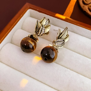 Détail macro de boucles d'oreilles vintage feuille d'or avec diamants et œil de tigre
