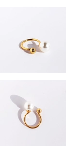 Detailed view of a gold U-shaped ring featuring a large white pearl and a small gold bead