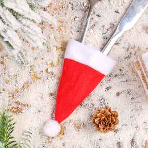 Mini Christmas hat cutlery holder made of red felt on rustic wooden festive background